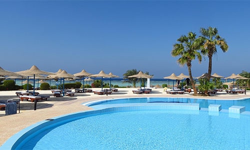 Hotel resort pool with tables and chairs by beach